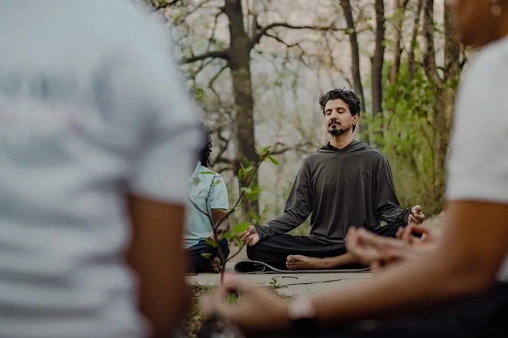 A student folding into deep, unhurried asana practice inside the Adhiroha shala