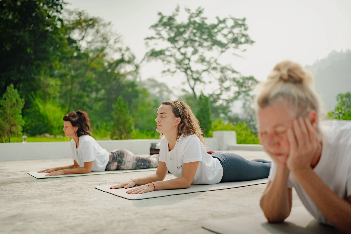 Participants practising asana outdoors on mats in the morning light at Adhiroha
