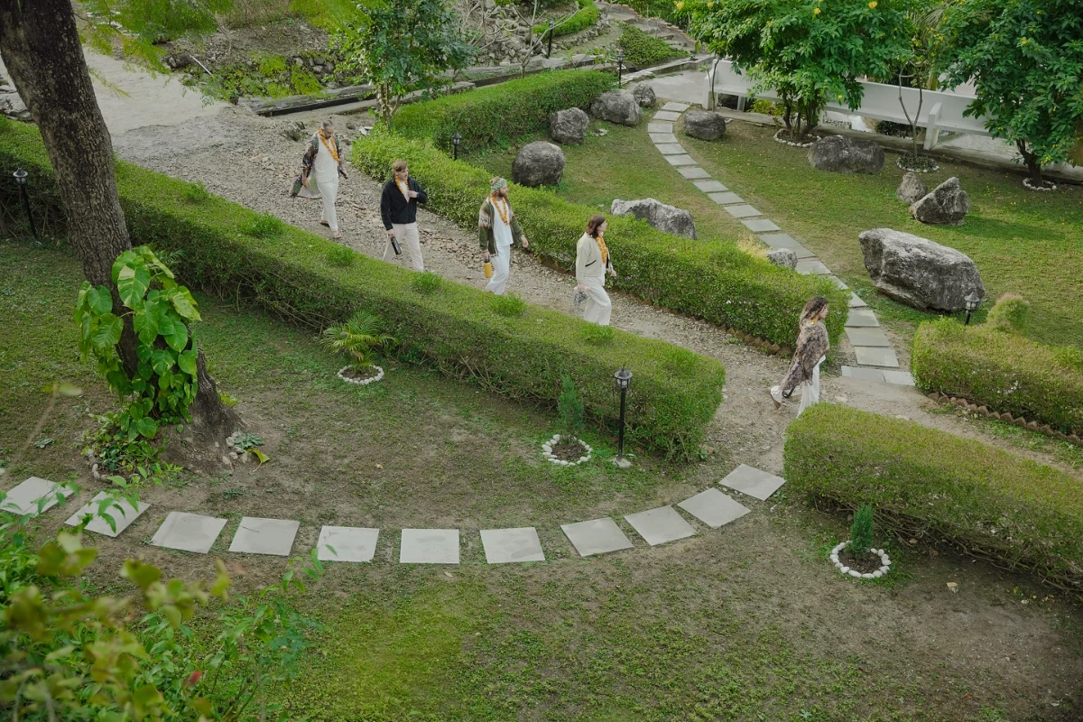 Participants walking mindfully through the green gardens of the Adhiroha ashram in Rishikesh
