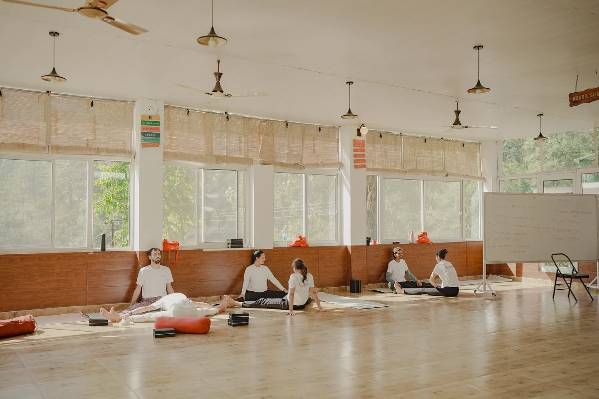 Participants seated in quiet practice inside the sunlit Adhiroha yoga shala