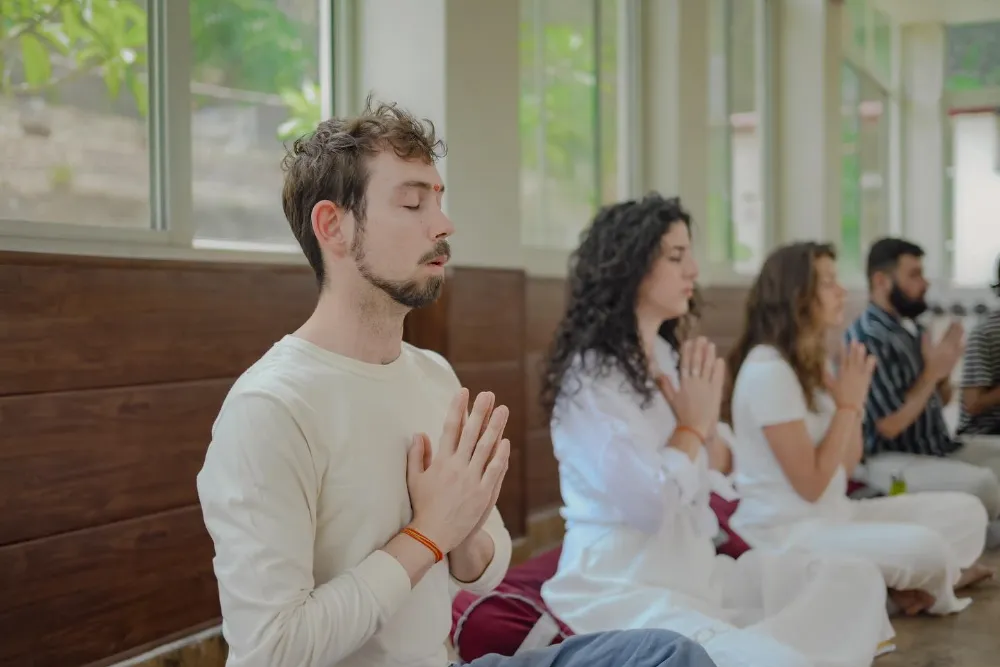A teacher guiding a student through an Ashtanga posture on the Ashtanga and Vinyasa course