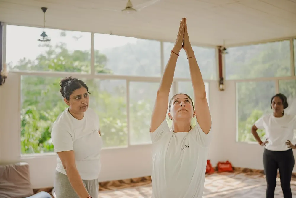 A student folding into deep, unhurried asana practice inside the Adhiroha shala