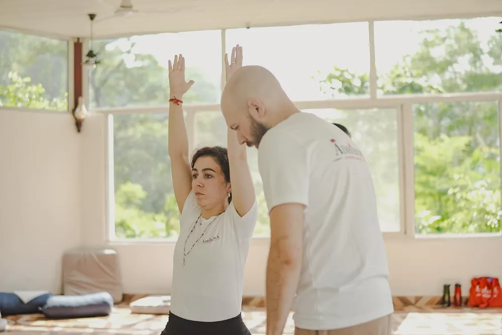 Teacher adjusting a student in a deep backbend during ashtanga class