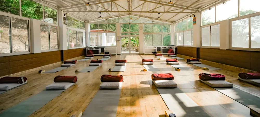 Sunlit, well-ventilated and sanitised yoga shala at Adhiroha with mats and bolsters laid out