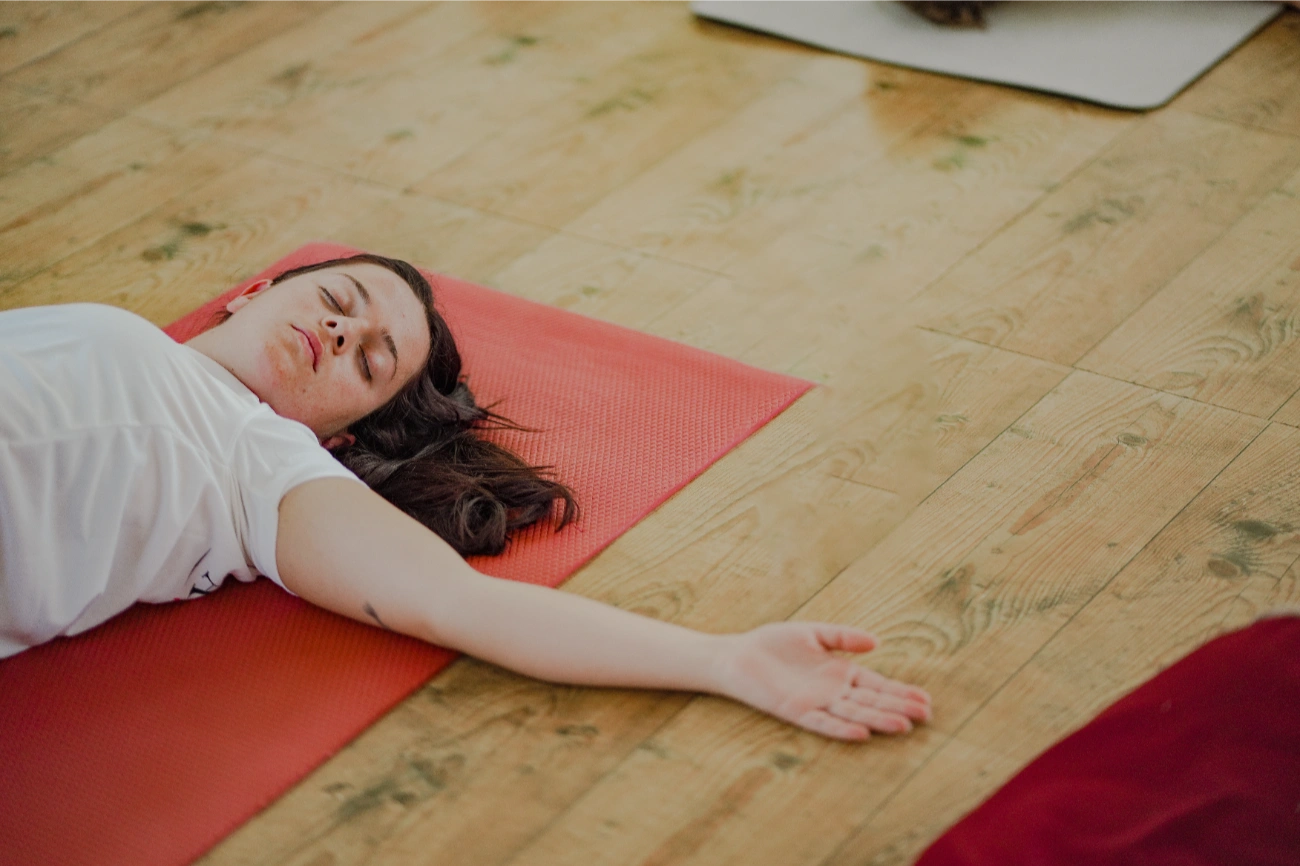 Student resting in a supported yin posture on the mat