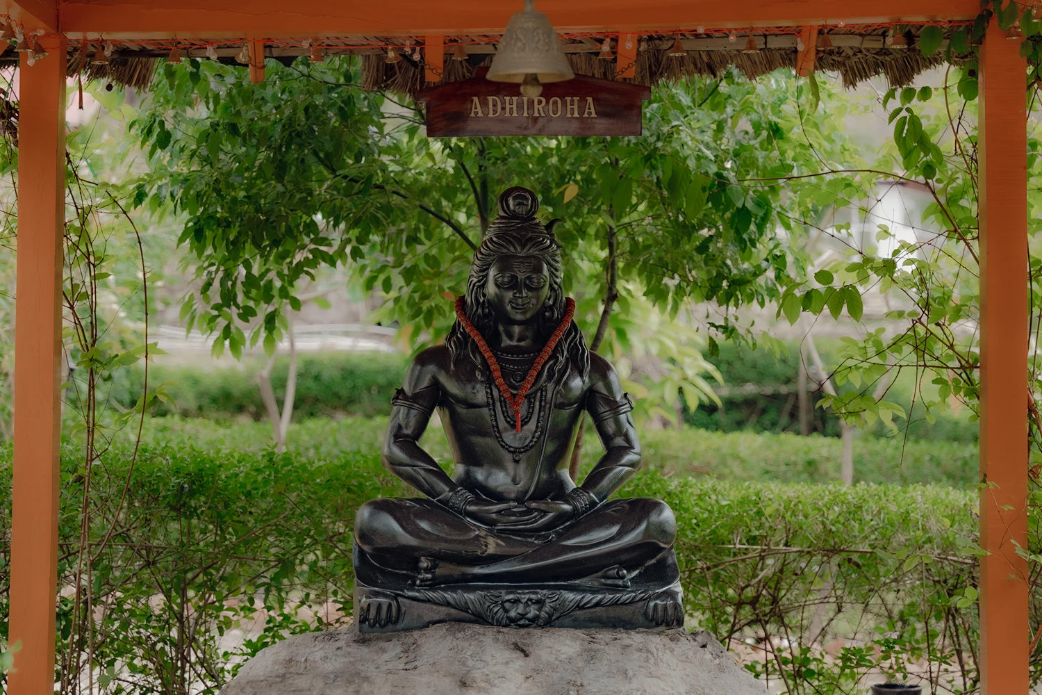 The Shiva statue seated beneath the Adhiroha bell canopy in the ashram gardens, Rishikesh
