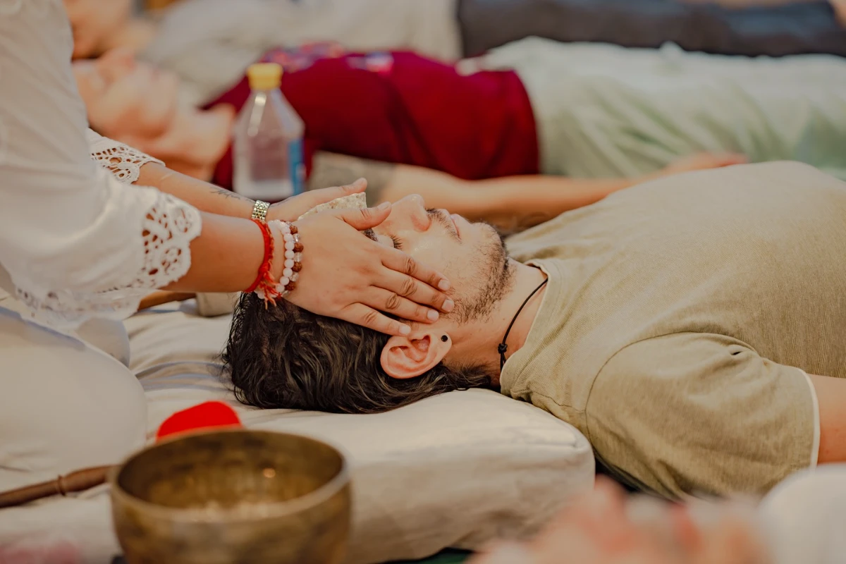 A healer&rsquo;s hands cradling a student&rsquo;s head during sound therapy
