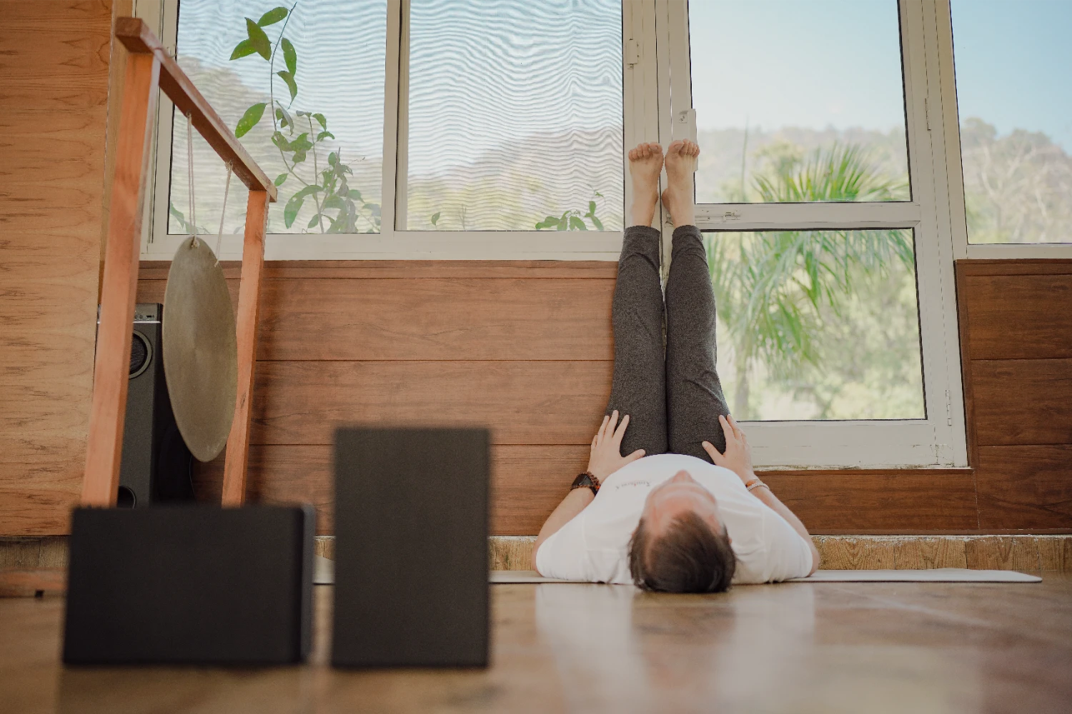 A student resting in a calm restorative practice by the shala window